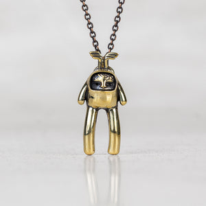 Gold creature with wings on its head charm pendant on a chain against a white background