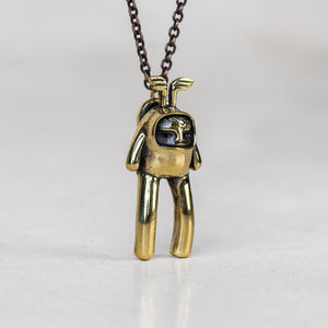 Gold creature pendant charm with wings on its head attached to a chain on a white background