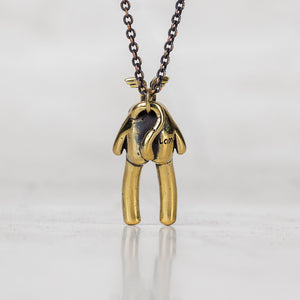 Back view of a gold creature pendant necklace on a chain on a white background