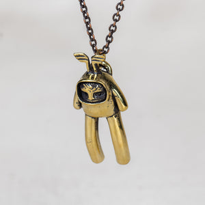 Gold creature charm pendant with wings on its head hanging on a chain against a white background