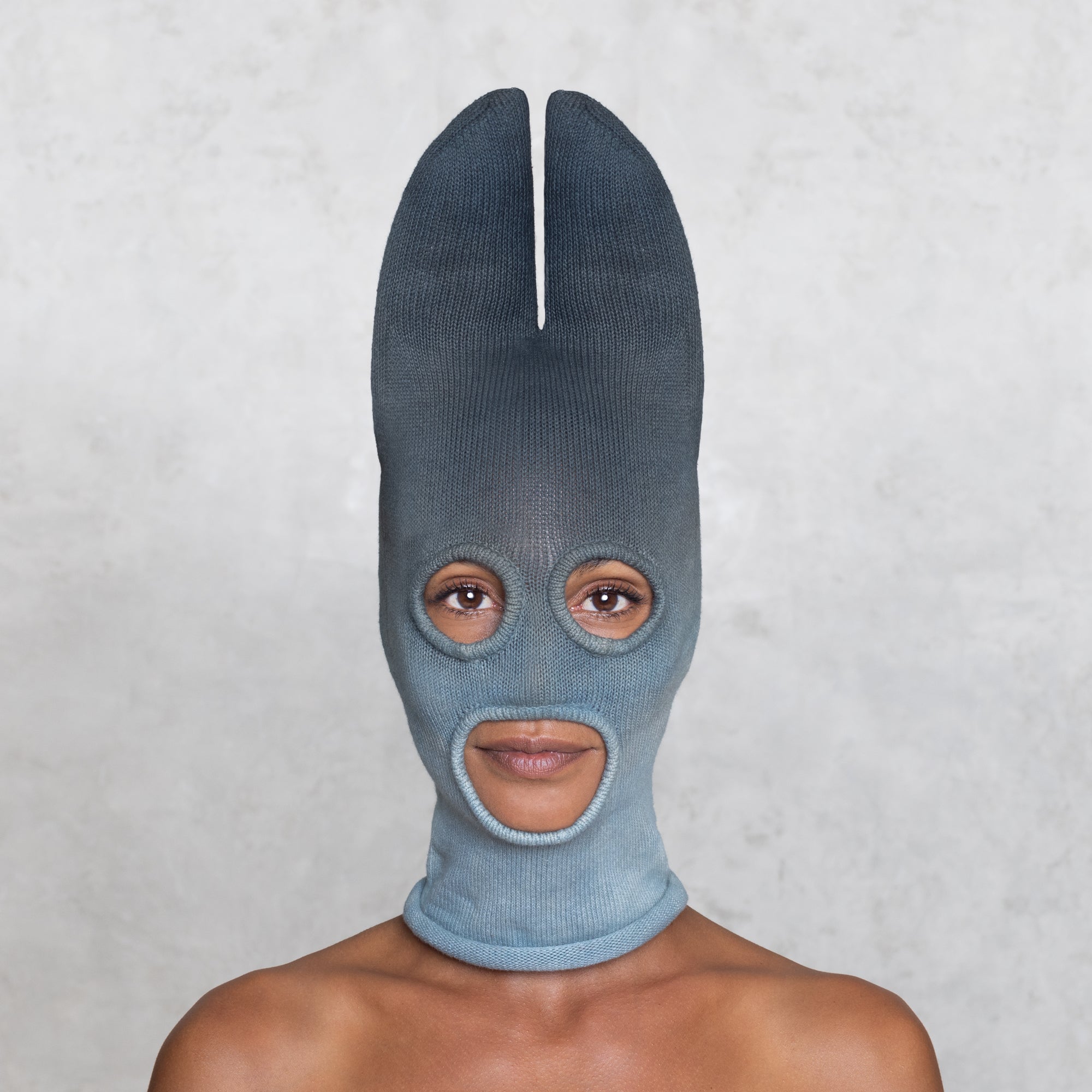 A woman from the shoulders up wearing a cotton Knit Bat balaclava in faded indigo