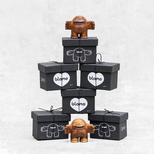 Box tower with 2 wooden toys with a friendly facial expression, standing upright with arms outstretched.