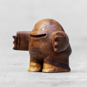 A wooden toy with a friendly facial expression and brass eyes, standing upright with arms outstretched.