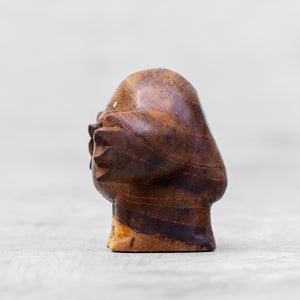 A wooden toy with brass eyes, standing upright with arms outstretched.