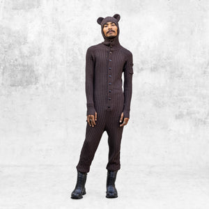 Person wearing a brown hooded knit bear onesie standing against a light gray background