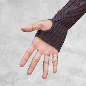 Persons hand outstretched with their thumb through the thumbhole of a brown knit sweater