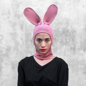 Person wearing a pink bunny balaclava with tall ears against a light gray background