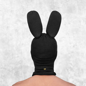 Person wearing a black mask with tall bunny ears against a light gray background