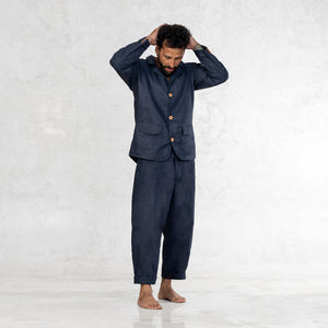 Man standing barefoot in an Indigo Linen suit with his hands behind his head. 