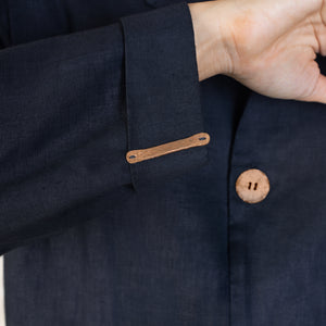 The details of an elongated copper button attached to the cuff of an Indigo Linen suit. 