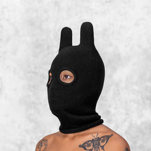 Person wearing a black balaclava mask with rounded ears against a light gray background