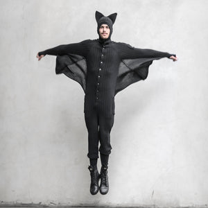 A person wearing a black BLAMO bat onesie jumping with arms spread out in a V-shape, resembling bat wings.