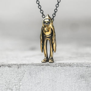 BLAMO Birdman pendant charm on a chain standing on a concrete ledge