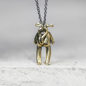 Creature with antlers and a tail charm pendant attached to a chain standing on a gray concrete ledge