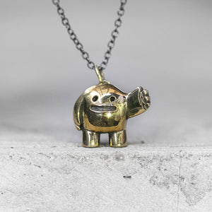 BLAMO Slap charm pendant on a chain standing on a concrete ledge