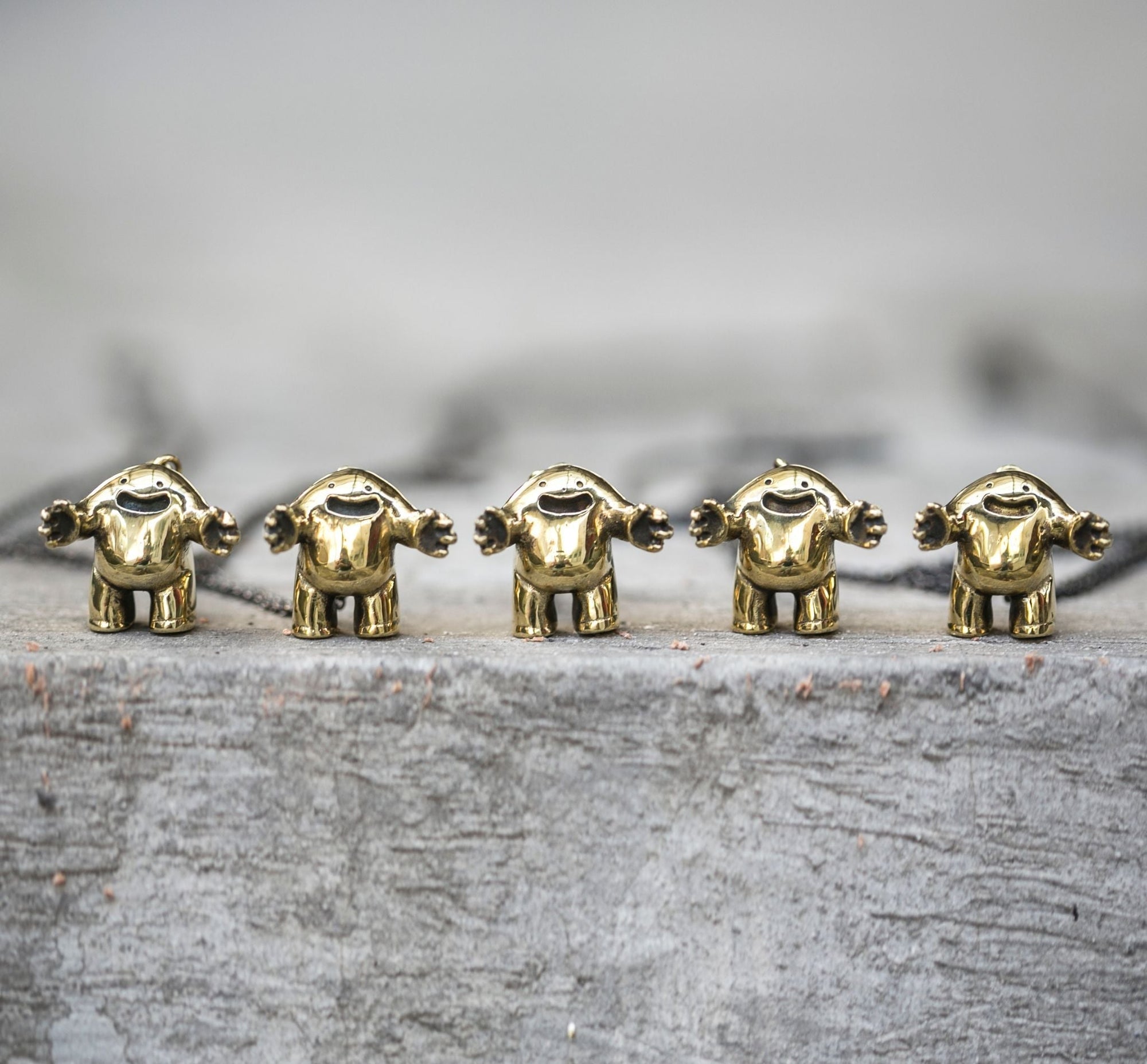 Small brass hugs charms lined up side by side