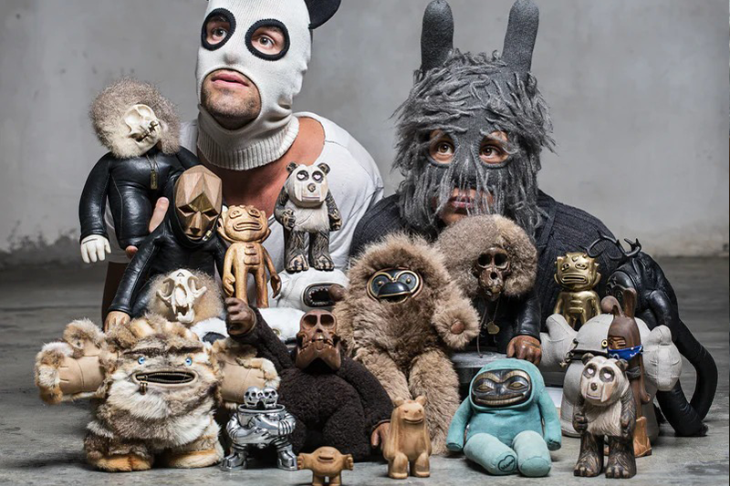 A man and woman in balaclavas with a bunch of toy sculptures