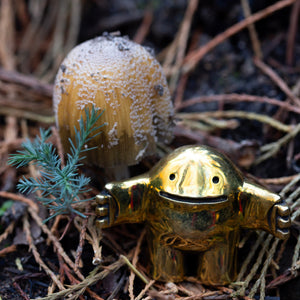 Gold-colored figurine on a natural background with a plant and textured surface