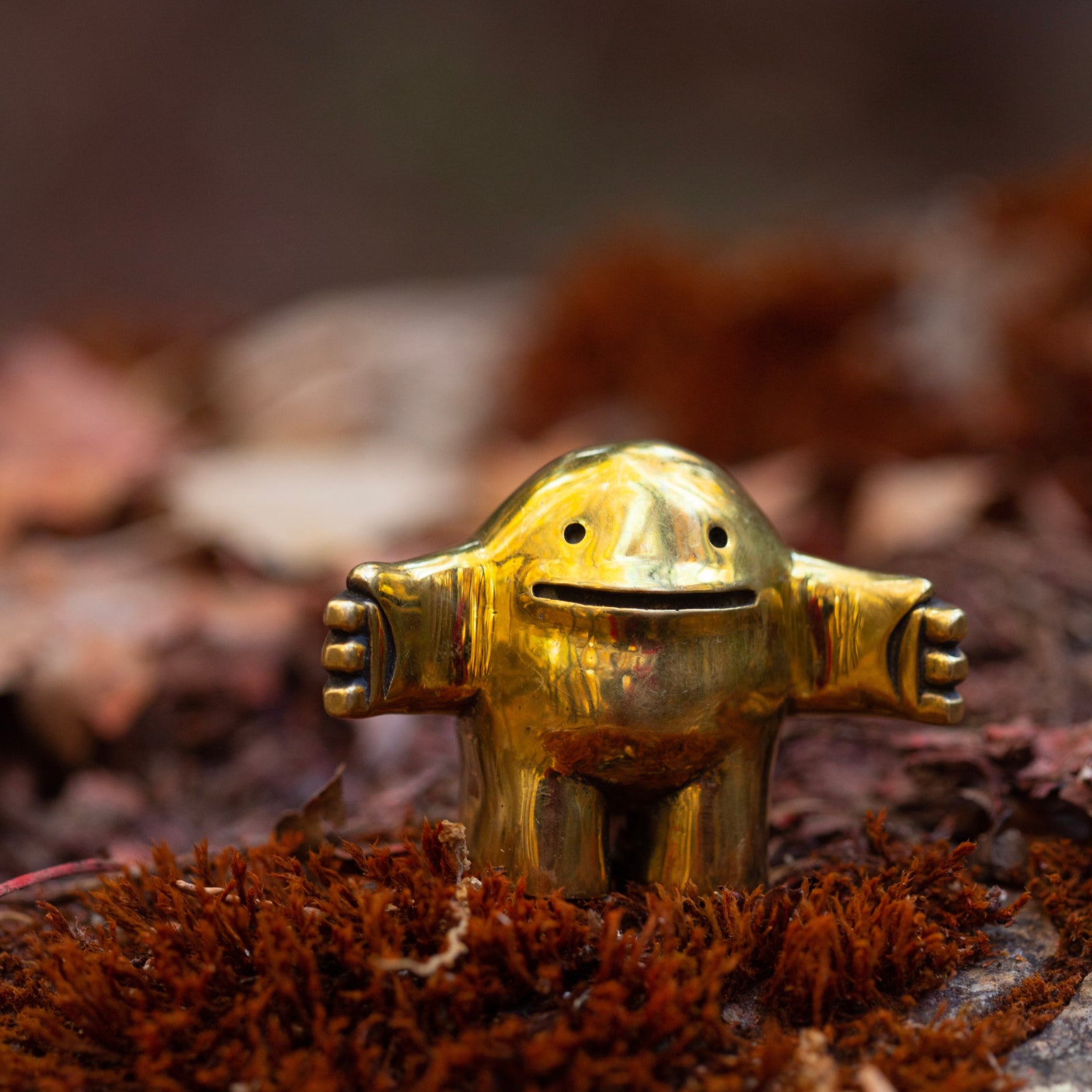 Gold figurine on a natural surface with a blurred background