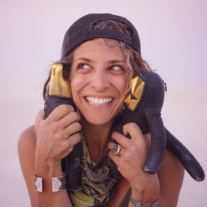 Person smiling and holding two leather figurines up to their face