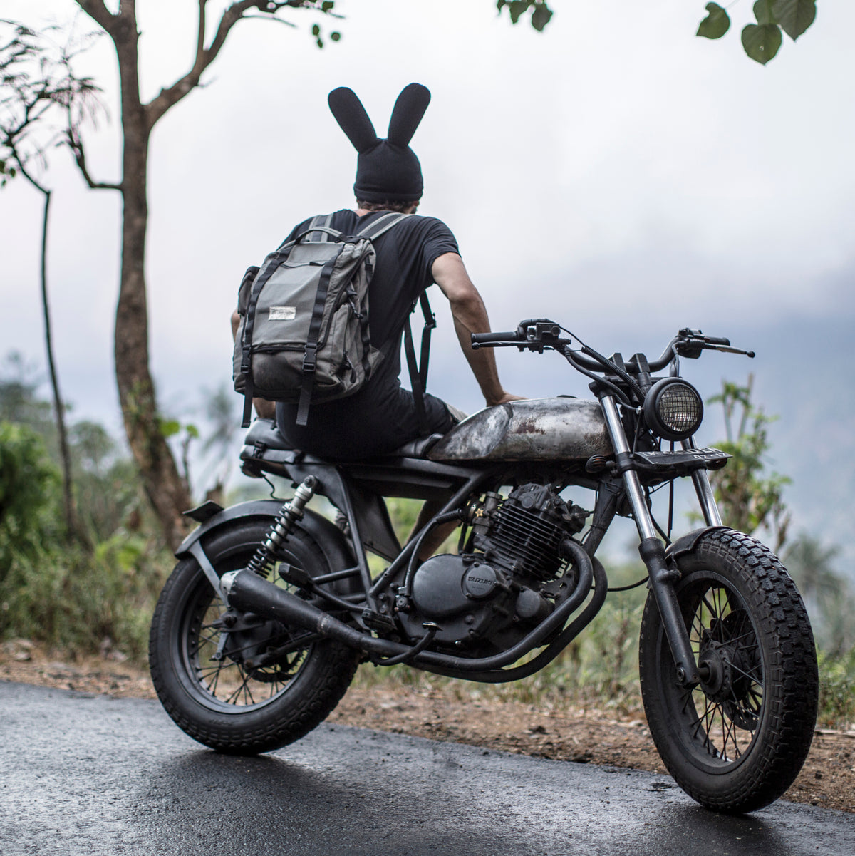 Person facing backwards wearing a bunny  beanie sitting on a motorcycle