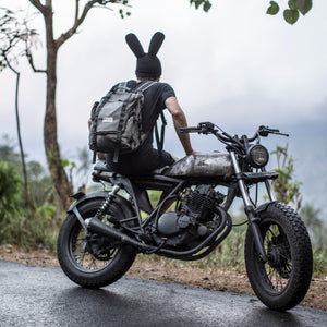 Person facing backwards wearing a bunny  beanie sitting on a motorcycle