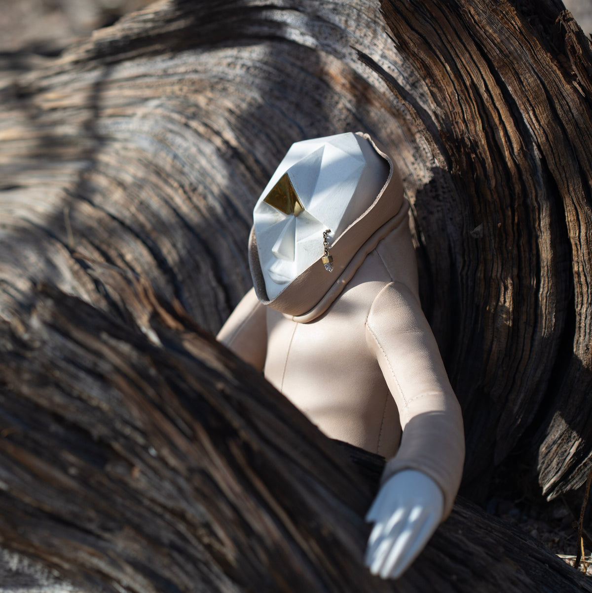 Ceramic and leather figurine sitting in a wooden tree