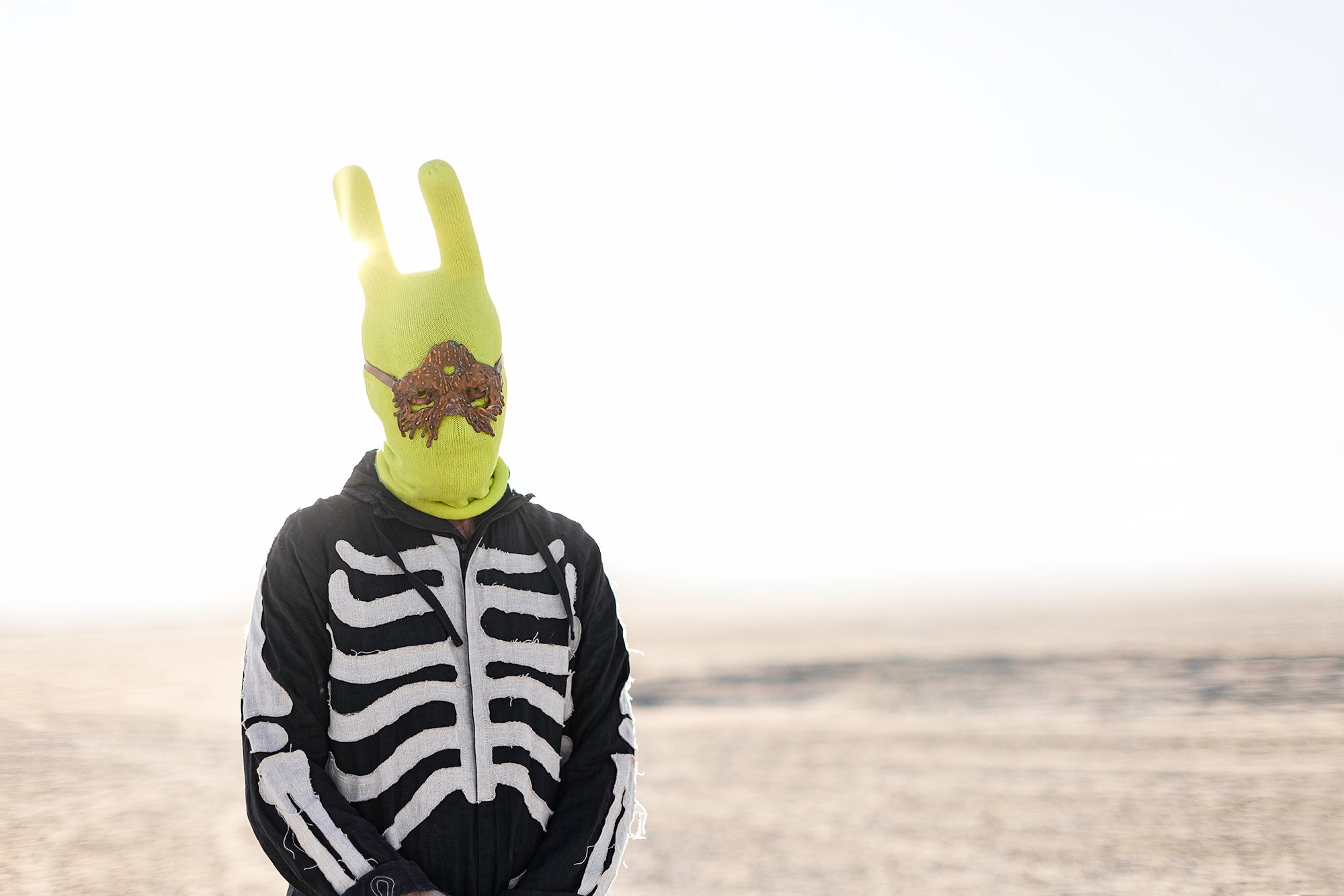 a man in a skeleton suit and a lime green balaclava