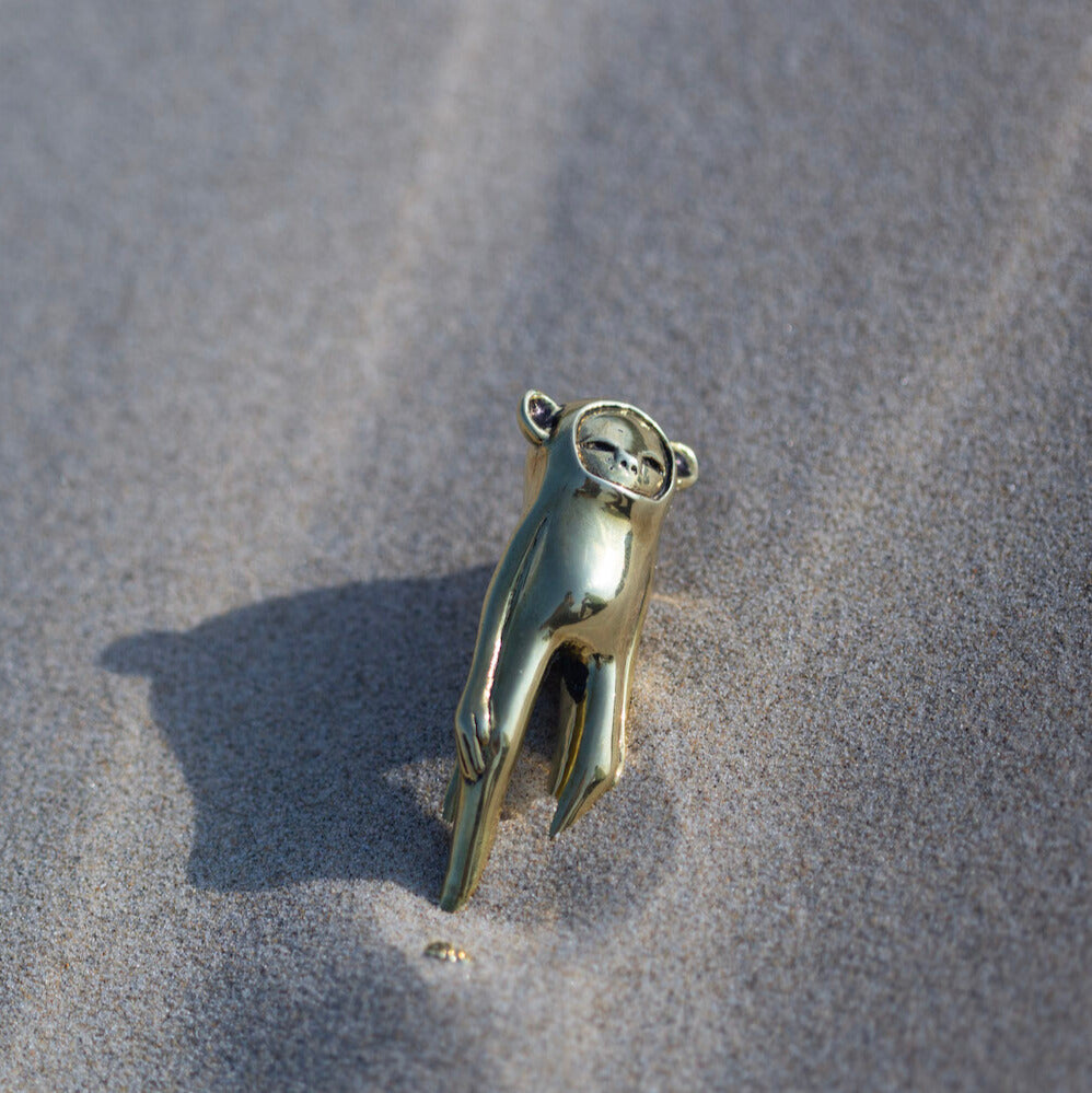 Gold hand-shaped pendant on a sandy surface