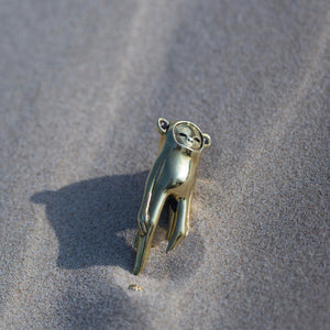 Gold hand-shaped pendant on a sandy surface