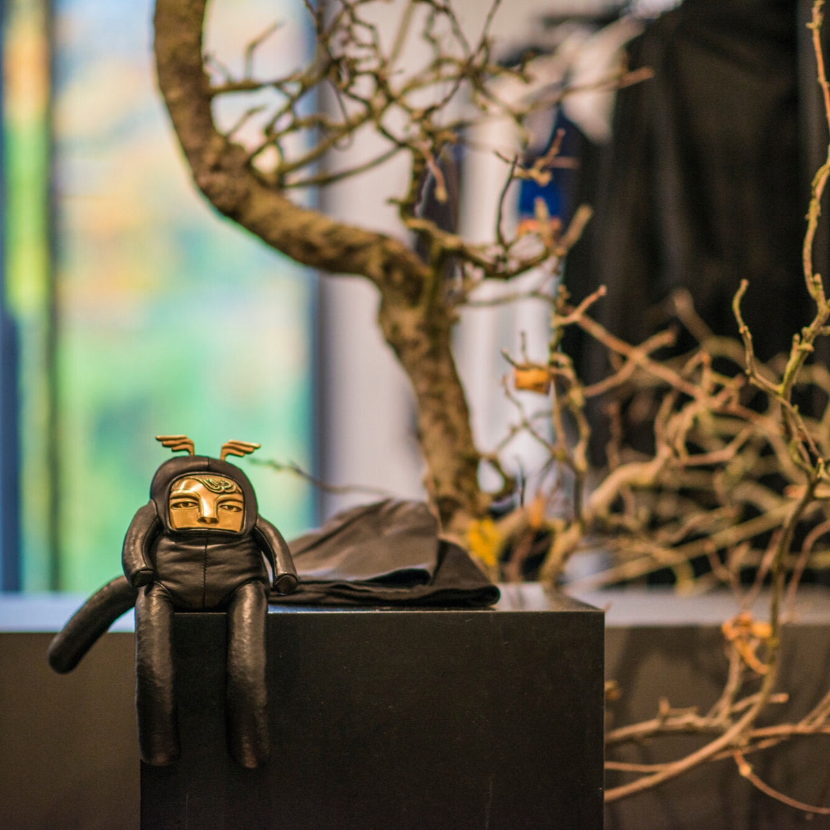 Leather and brass figurine sitting on a block with a blurred background