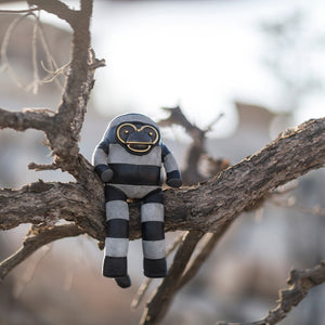 Leather striped toy sitting on a tree branch with a blurred natural background