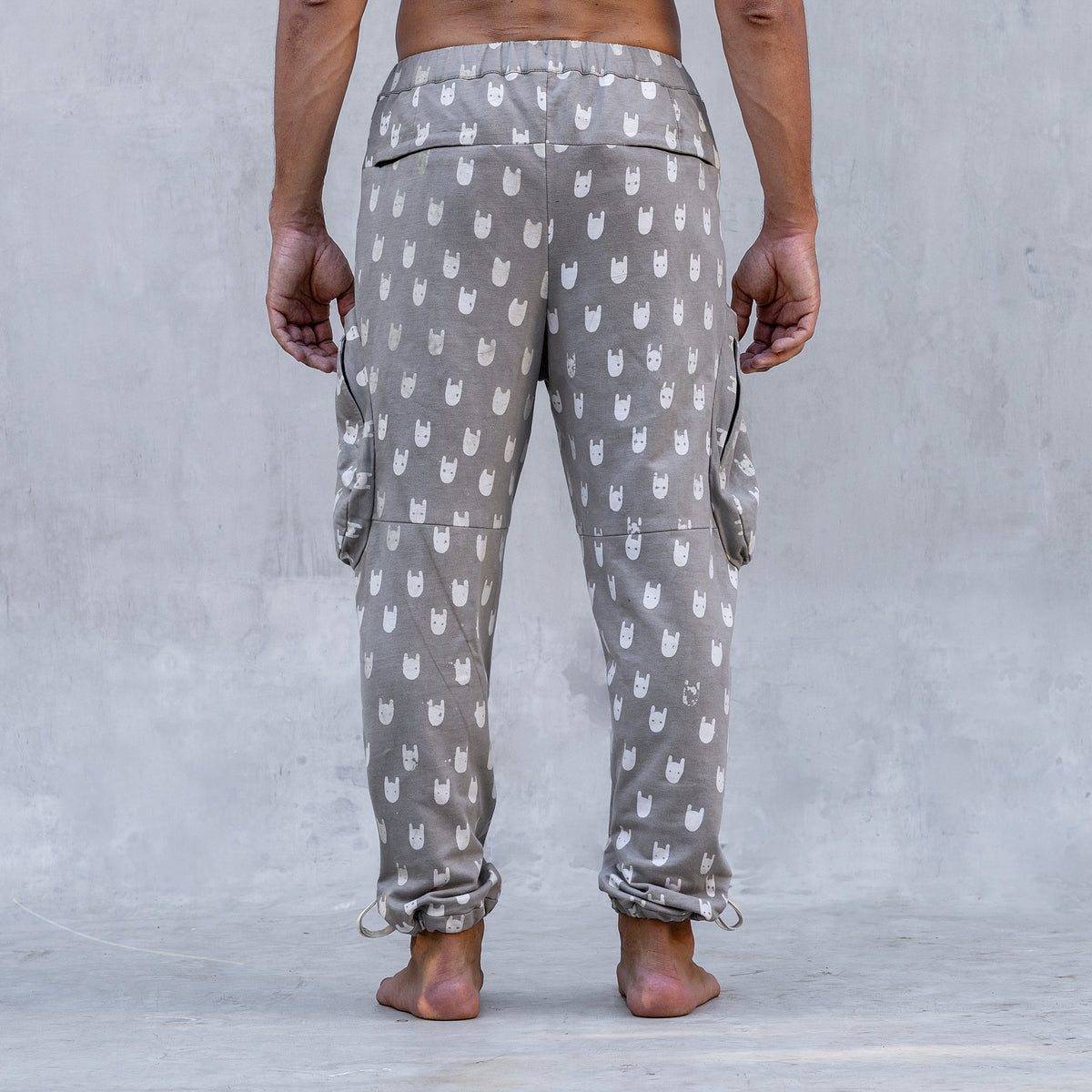 A man wearing a pair of BLAMO socky all-over-print sand colored pants shown from the back from the waist down
