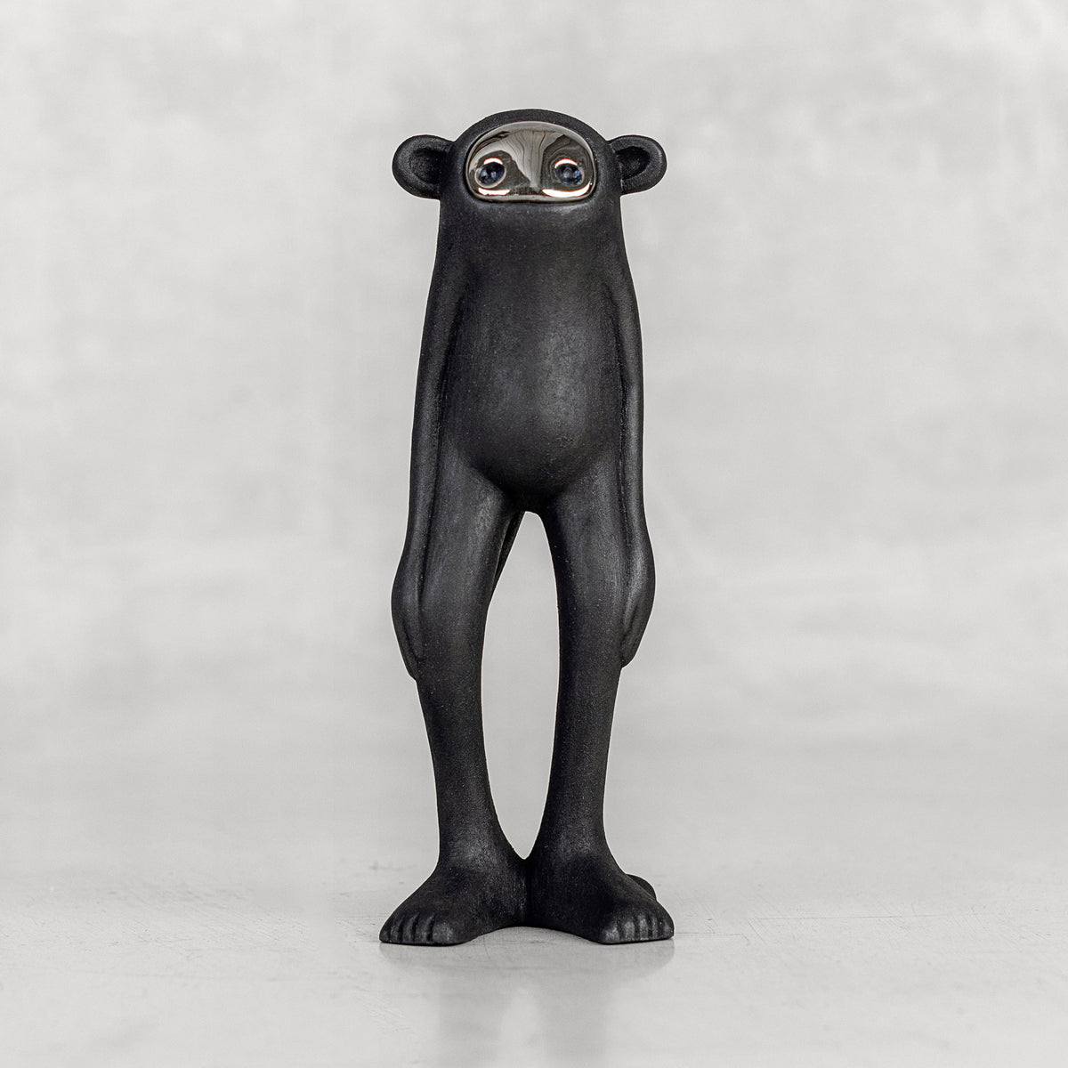 Black monkey figurine with a silver face on a white background