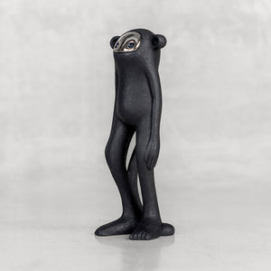 Black monkey figurine with a silver face facing sideways on a white background