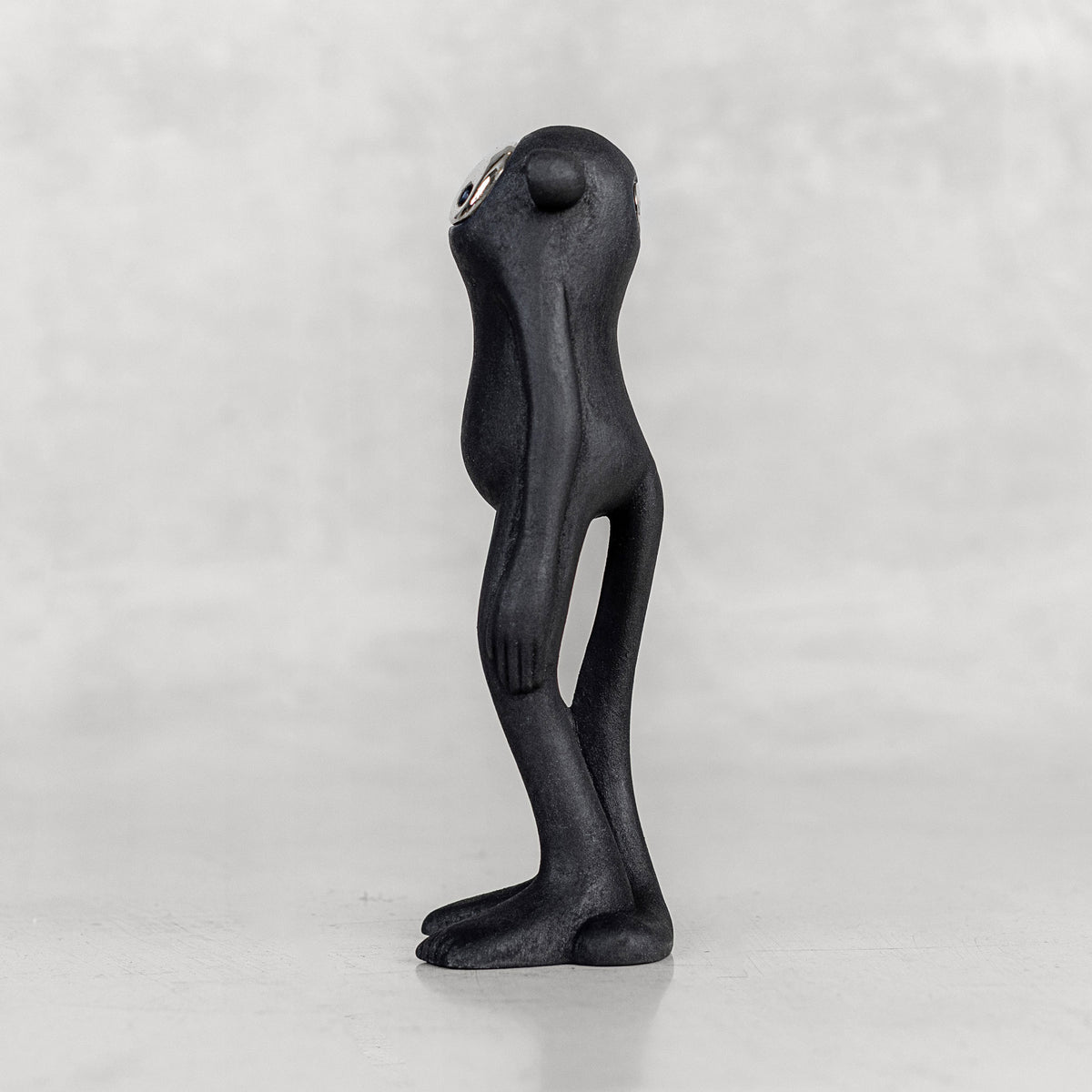 Side view of a black monkey figurine with a silver face on a white background