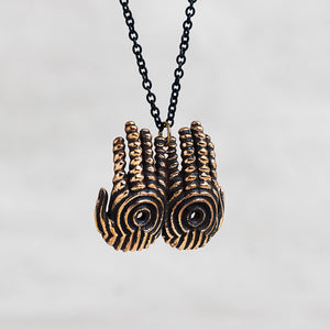 A pair of hands pendant necklace with a black chain, featuring a textured bronze finish with black recessed detailing.