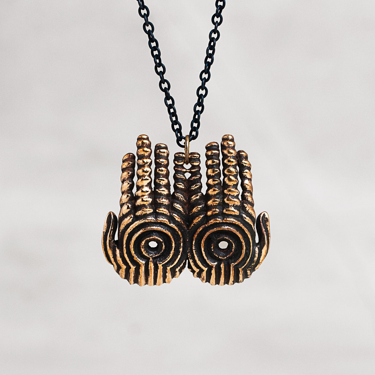 Copper hand pendant necklace charms with a black chain, shown against a neutral light gray background.