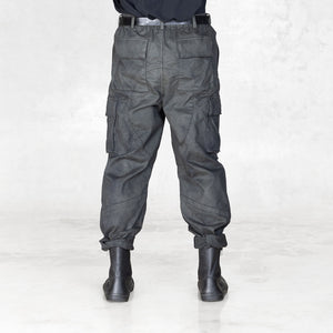 Back view of a person wearing dark gray cargo pants and black boots on a white background