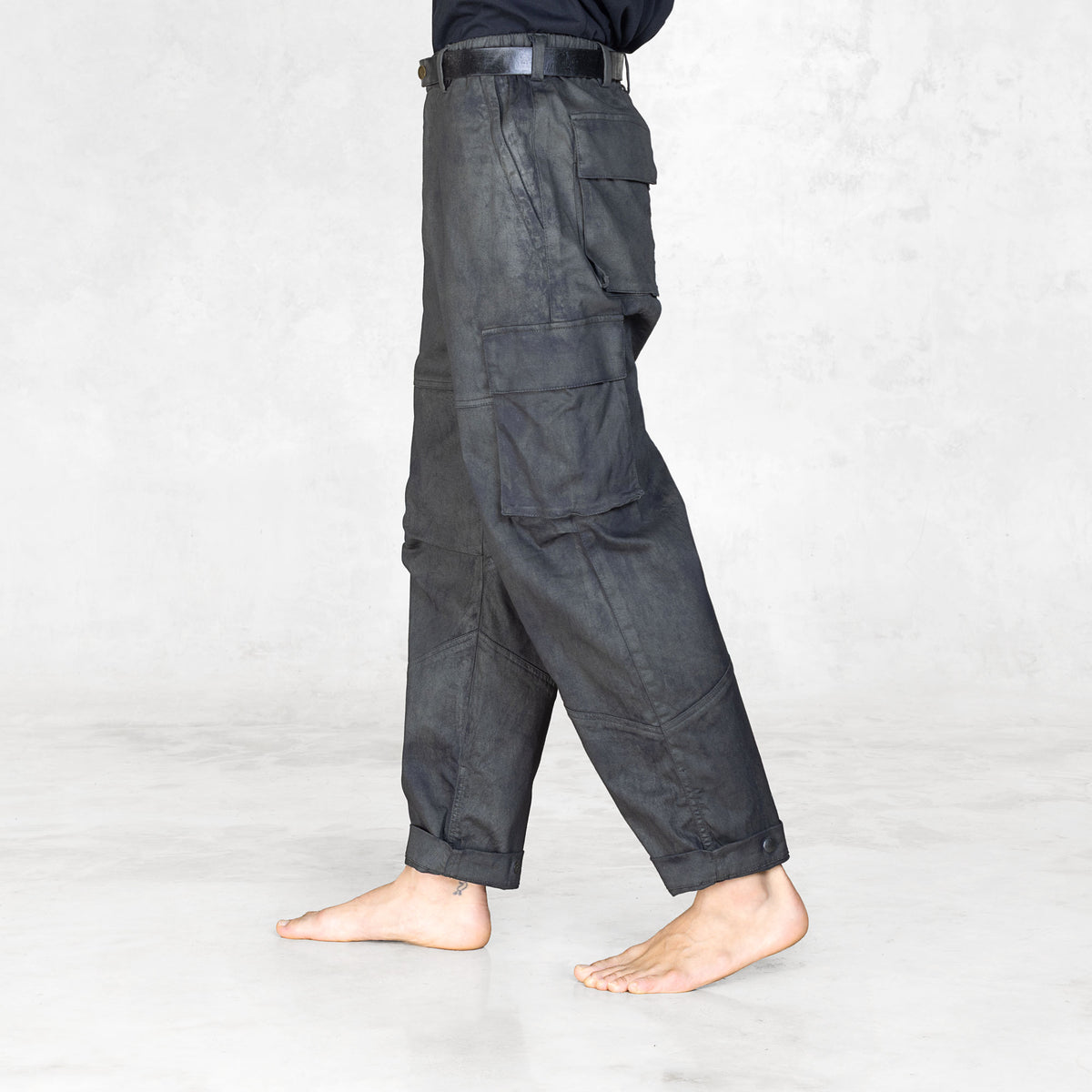 Side view of a person wearing dark gray cargo pants on a white background
