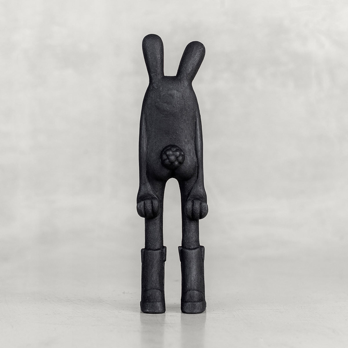 Back view of a black bunny figure on a white background