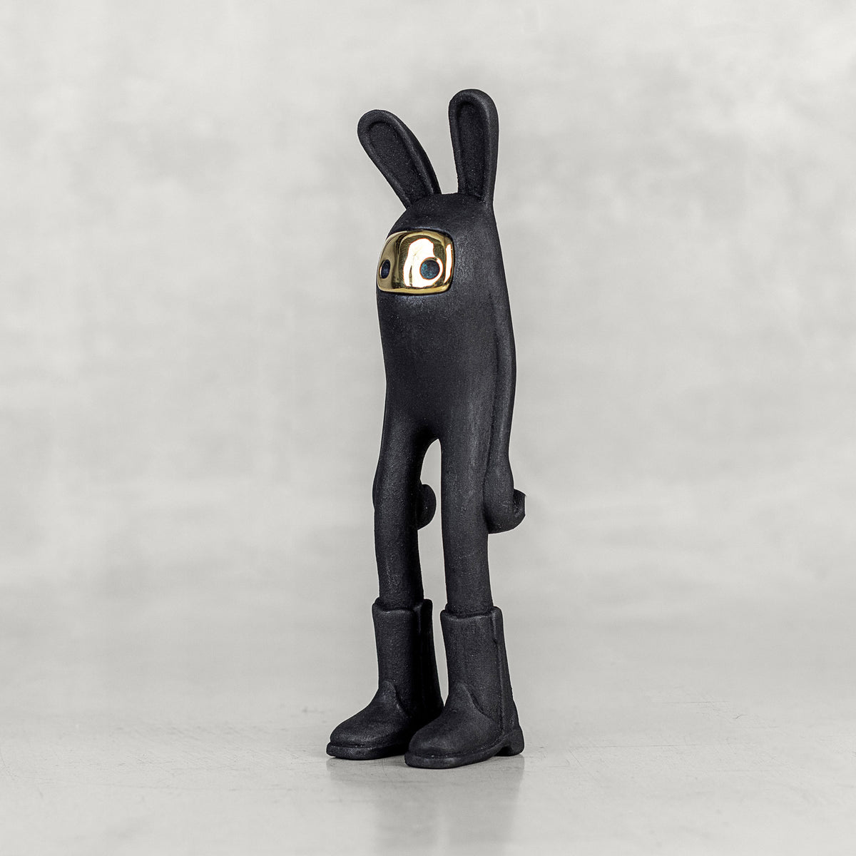 Quarter view of a black bunny figure with a brass face on a white background