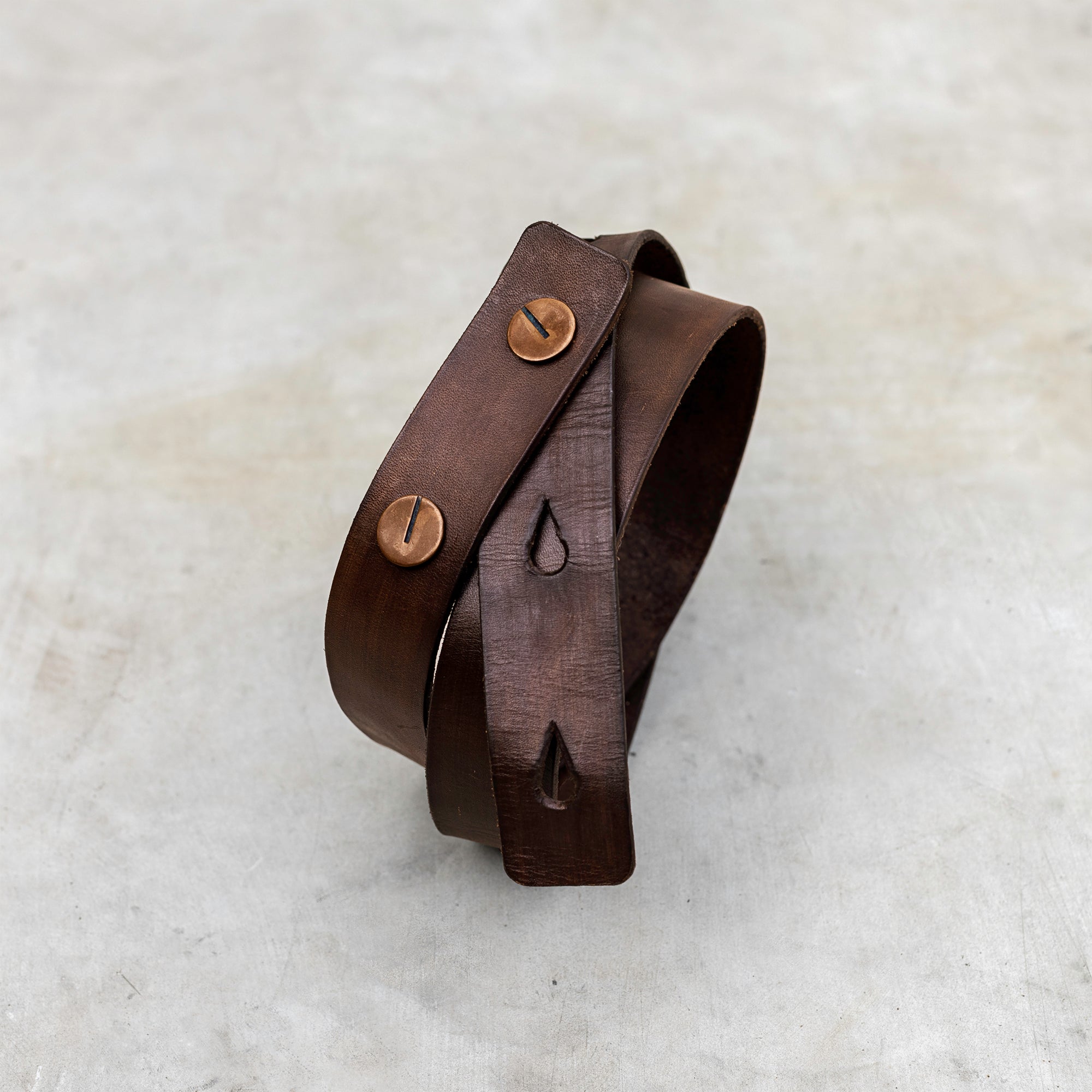 A brown leather belt with round copper buttons