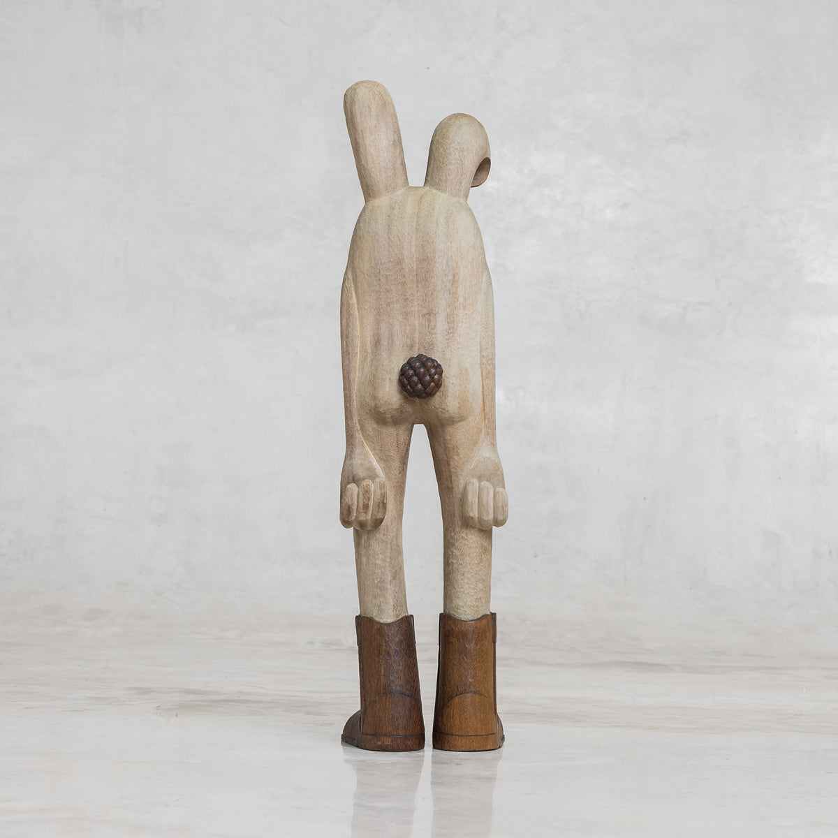 Wooden bunny rabbit figurine with brown boots on a light gray background