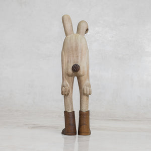 Wooden bunny rabbit figurine with brown boots on a light gray background