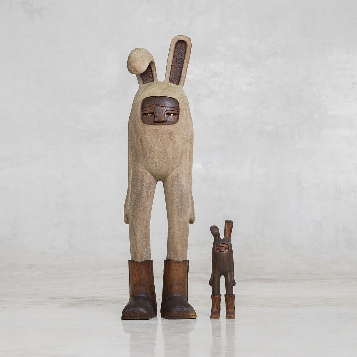 Two wooden bunny rabbit figures, one larger and one smaller, on a light gray background
