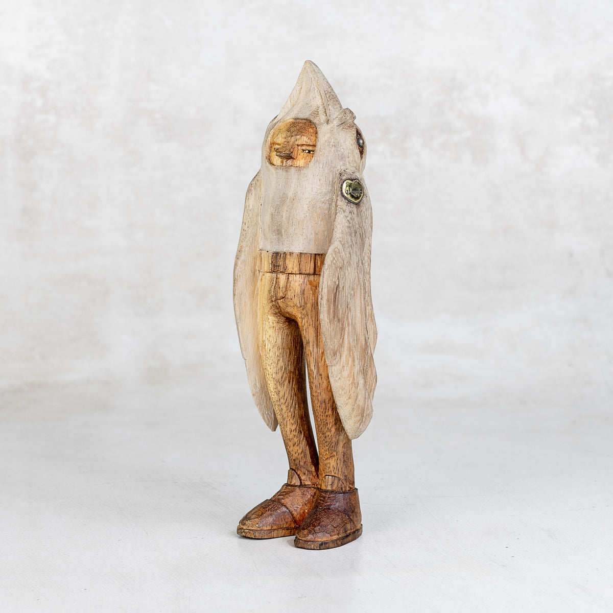 Wooden sculpture of a bird-like creature with humanoid body on a white background