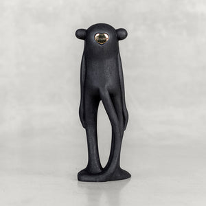 Back view of a black monkey figurine with a brass emblem on a white background