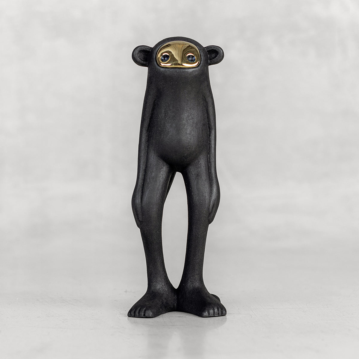 Black monkey figurine with a brass face on a white background