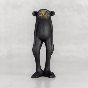 Black monkey figurine with a brass face on a white background